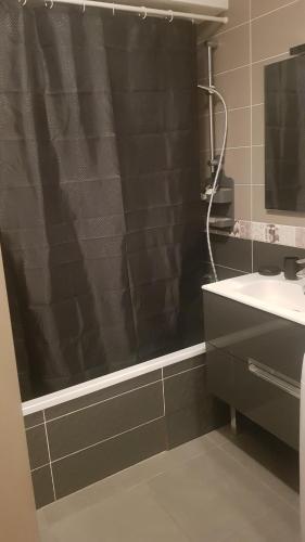 La salle de bains est pourvue d'une douche avec rideau de douche noir. dans l'établissement Entre lac et montagnes, à Neuvecelle