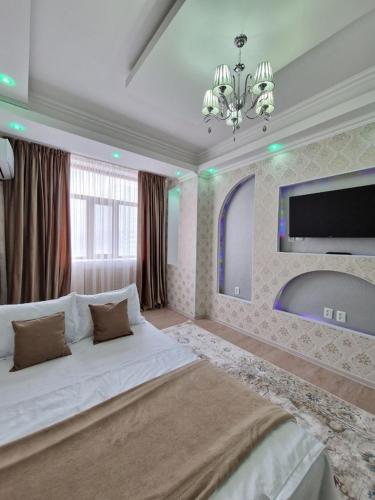 ein großes Schlafzimmer mit einem großen Bett und einem Kronleuchter in der Unterkunft Апартаменты в центре города in Aqtau