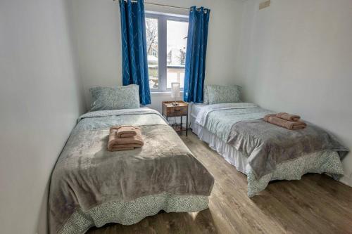 2 camas en una habitación con cortinas azules en Modern Condo 2BR 4 beds AC Wi-Fi Free Parking, en Laval