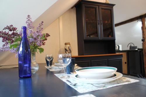 einen Tisch mit einer blauen Flasche sowie Teller und Gläser in der Unterkunft Dom Pracy Twórczej Macondo 