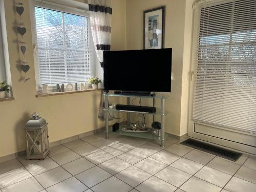a living room with a flat screen tv and two windows at FeWo Sonnenblick - Meer Urlaub in Fehmarn
