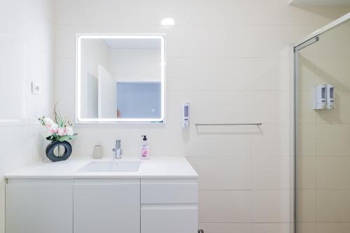 ein weißes Badezimmer mit einem Waschbecken und einem Spiegel in der Unterkunft OCEAN VIEW House (airport&city) in Ponta Delgada