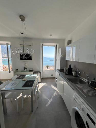 - une cuisine avec un évier et une table offrant une vue sur l'océan dans l'établissement Studio magnifique vue mer, à Menton