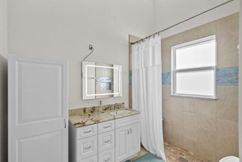 a white bathroom with a sink and a window at 2/1 Riverside Retreat with Loft in Fort Pierce