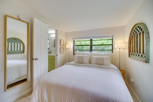 a white bedroom with a bed and a mirror at Vero Beach Studio with Shared Patio about 3 Mi to Beach! in Vero Beach