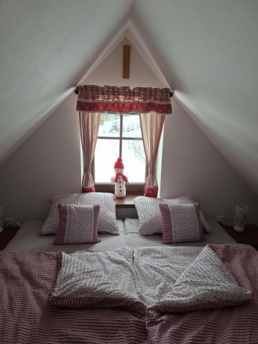 een slaapkamer met een bed met kussens en een raam bij Chalupa U Křížku Říčky v Orlických horách in Říčky