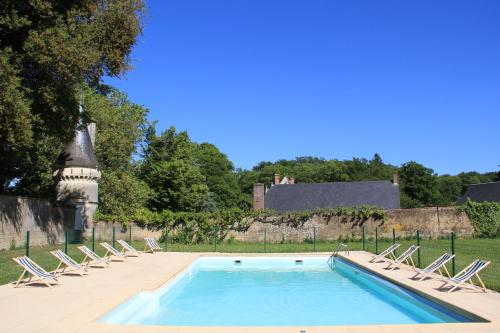 une piscine avec des chaises longues et un château en arrière-plan dans l'établissement Château d'Amenon à 35mn du circuit du Mans et 35mn de Tours, à La Chapelle-aux-Choux