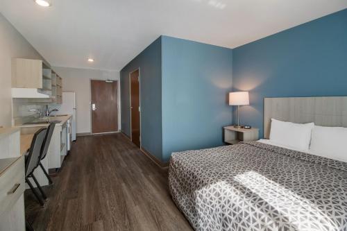 a bedroom with a bed and a blue wall at WoodSpring Suites Fort Myers - Cape Coral in Fort Myers