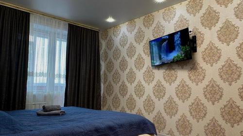 - une chambre avec un lit et une télévision murale dans l'établissement ЖК Альфа Бета, à Kostanay