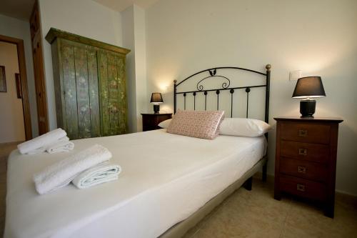 a bedroom with a large white bed with towels on it at Águilas Delicias Piscina Wifi AC Parking Gratis in Águilas
