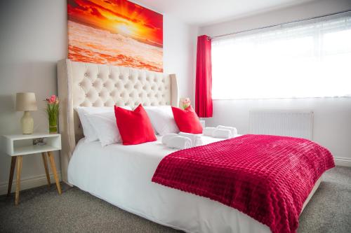 a bedroom with a large white bed with red pillows at Lucky Home - Ideal for Trade, Consultants & Family - Near Alton Towers, 3 Bedrooms - 4 Beds - 5 People in Stoke on Trent