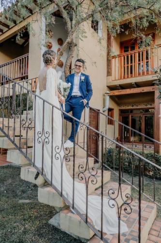 a bride and groom standing on the stairs of a building at VoyAca Hotel - Alfareria in Villa de Leyva