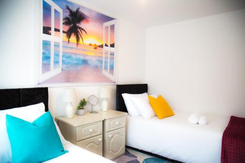 a bedroom with two beds and a picture of the beach at Lucky Home - Ideal for Trade, Consultants & Family - Near Alton Towers, 3 Bedrooms - 4 Beds - Max 5 Guests in Stoke on Trent