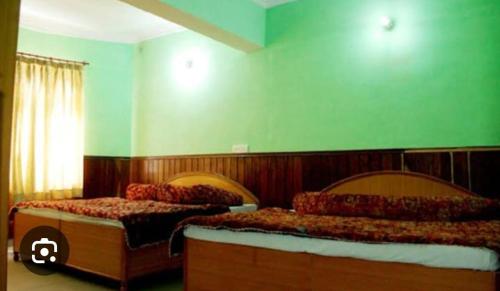 2 camas en una habitación con paredes verdes en OM Kutir Badrinath Dham, en Badrīnāth