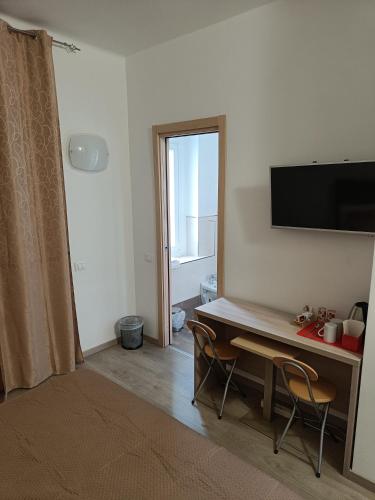 a room with a desk with two chairs and a television at Le Coccole in La Spezia