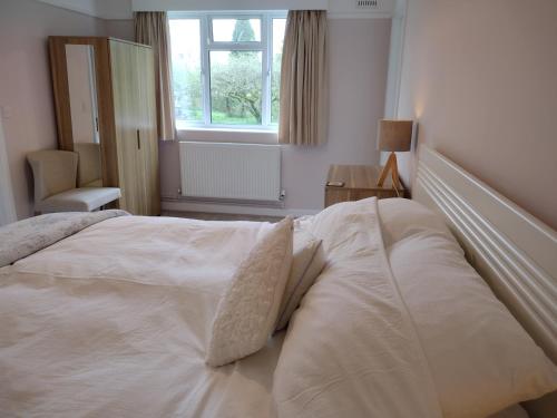 a large white bed in a bedroom with a window at Robin Hill Cottage in Amesbury