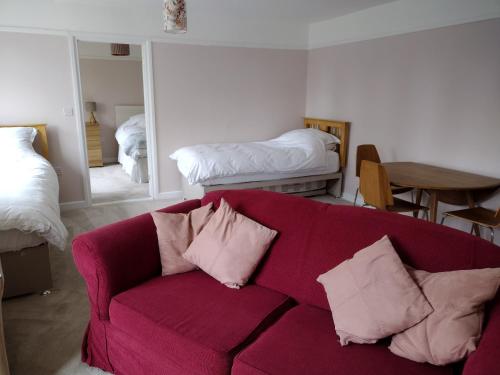 a living room with a red couch with pillows at Robin Hill Cottage in Amesbury