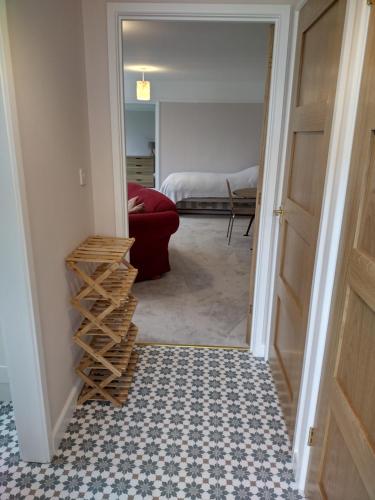 a hallway with a door leading into a room with a red couch at Robin Hill Cottage in Amesbury