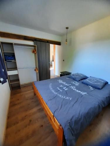 Schlafzimmer mit einem Bett mit blauer Decke in der Unterkunft Chez Marc in Lubersac