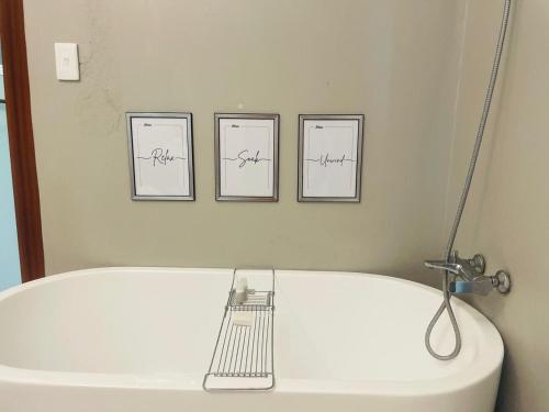 a bathroom with three pictures above a white tub at The Bliss Boutique in Louis Trichardt