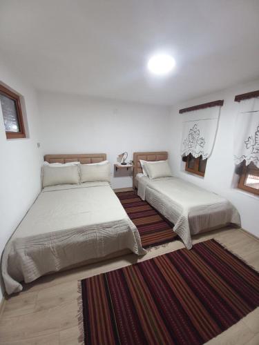 a bedroom with two beds and a rug at VodaHouse in Gjirokastër