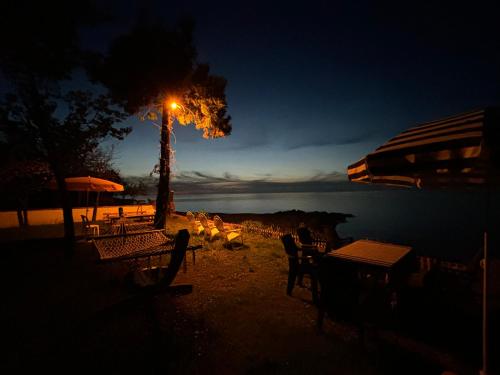 a lit street light next to a tree with tables and chairs at Seafront Apartment Rize-Ardeşen in Ardeşen