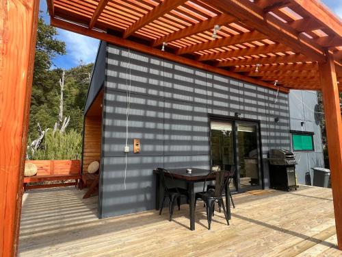 a patio with a table and chairs on a deck at Tiny House 2 a 3 per Malalcahuello Wifi Satelital in Malalcahuello