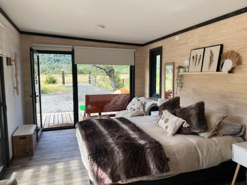 a bedroom with a large bed with a large window at Tiny House 2 a 3 per Malalcahuello Wifi Satelital in Malalcahuello