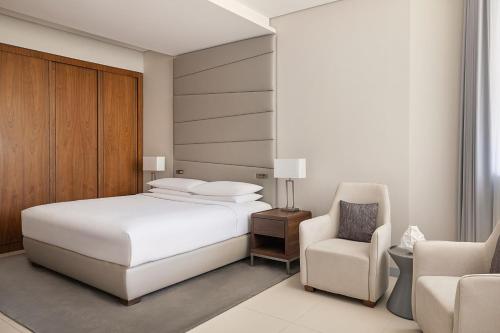 Marriott Riyadh Diplomatic Quarter في الرياض: غرفة نوم بسرير ابيض وكرسي
