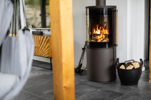 a fireplace in a room with a basket of logs at SAUERLAND CHALETS - "Die Chalets am Bergelchen" in Winterberg