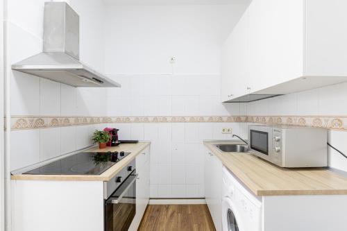 a white kitchen with a sink and a microwave at Apto Madrid Confort Centro in Madrid