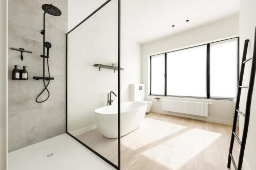 a bathroom with a tub and a shower with a window at Huis Velzeke in Zottegem