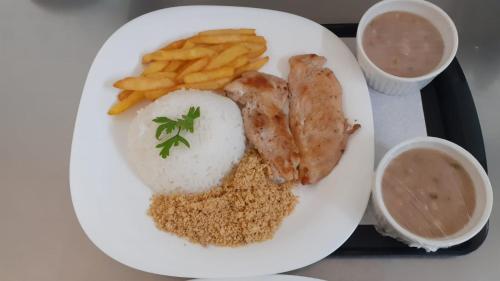 a plate of food with chicken rice and french fries at Karinho Hotel in Santo André