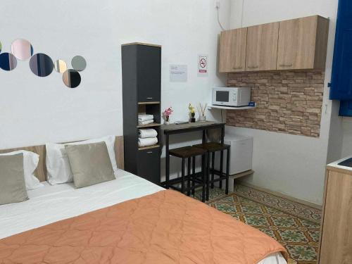 une chambre avec un lit et une cuisine avec un four micro-ondes dans l'établissement TRADITIONAL MALTESE STUDIO GZIRA, à Il-Gżira