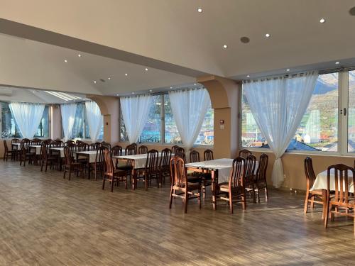 uma sala de jantar com mesas, cadeiras e janelas em Hotel Mountain View Inn em Gusinje