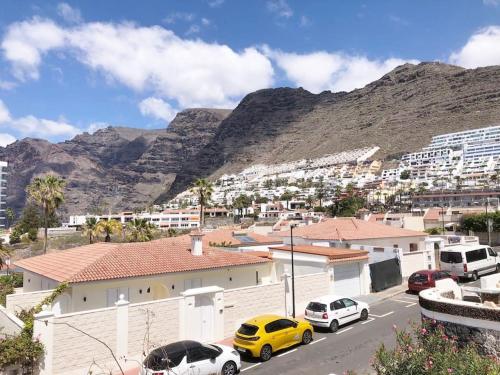 a city with cars parked in front of a mountain at Apartamento con impresionantes vistas en Los Gigantes - Crab Island in Puerto de Santiago