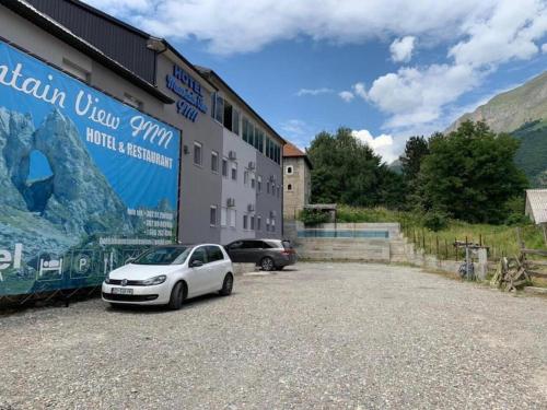 GusinjeHotel Mountain View Inn的一辆白色汽车停在一栋建筑物前