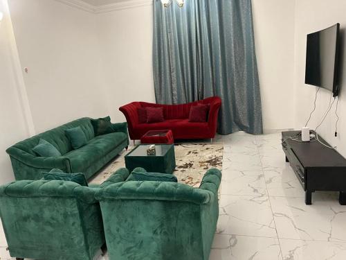 ein Wohnzimmer mit grünen Sofas und roten Stühlen in der Unterkunft 2bhk oasis tower in Ajman 
