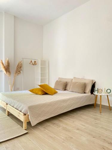 a white bedroom with a large bed with yellow pillows at Dimora La Coccinella - Accommodation in Muravera
