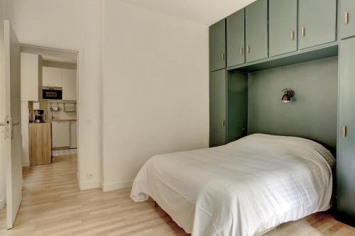 um quarto com uma cama branca e armários verdes em La Paroisse - Versailles em Versailles