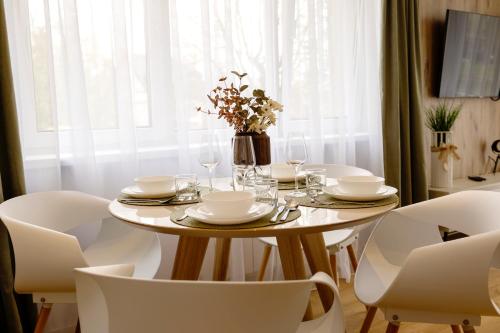 a dining room table with white chairs and a table with glasses at The Ground Floor - Apartament Centrum Augustów in Augustów