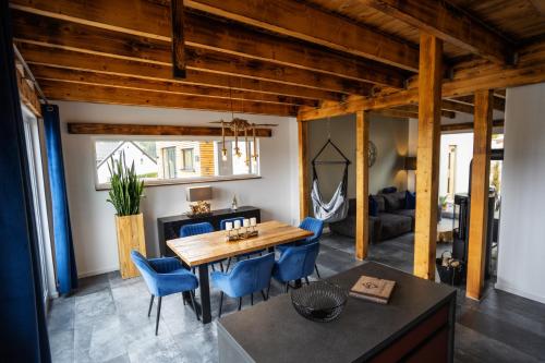 a dining room with a wooden table and blue chairs at SAUERLAND CHALETS - "Die Chalets am Bergelchen" in Winterberg