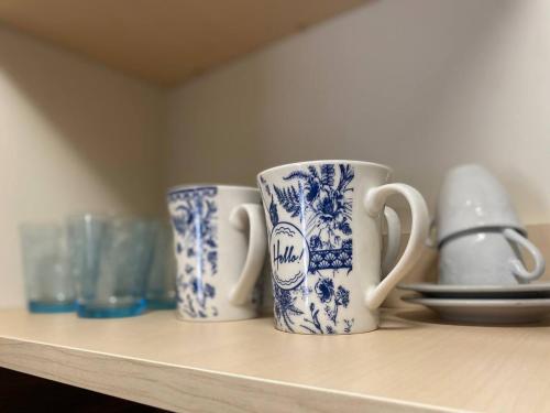 tres tazas azules y blancas sentadas en un estante en ApartVilla Trieste, en Trieste