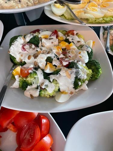 a plate of food with broccoli and tomatoes on a table at Villa Park in Siedlce