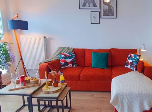 un salon avec un canapé rouge et une table dans l'établissement Appartement neuf - 3 chambres - 6 personnes - 73m² vue sur la ville, à Caen