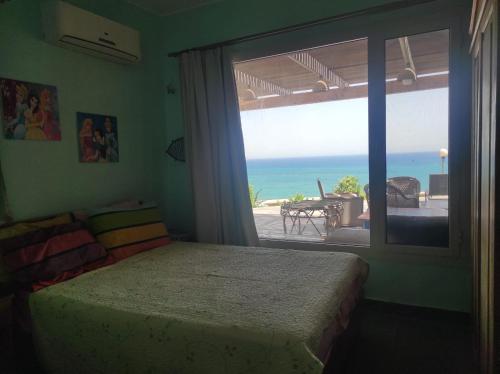 Schlafzimmer mit einem großen Fenster mit Meerblick in der Unterkunft Breath Taking View (For Families) in Ain Suchna