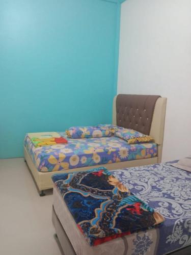 Habitación con 3 camas y pared azul. en penginapan alleo en Duku
