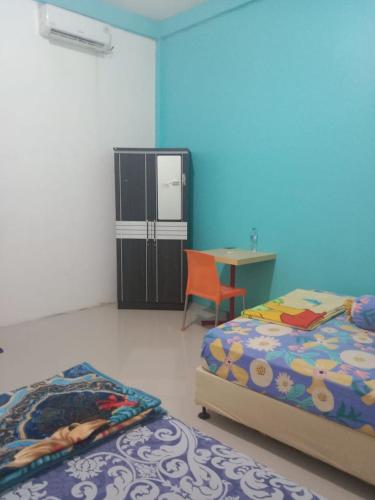 1 dormitorio con 2 camas, escritorio y nevera en penginapan alleo en Duku