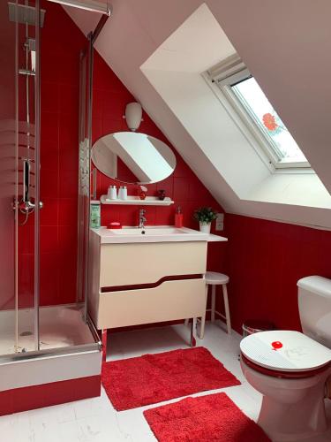 La salle de bains est pourvue de murs rouges, d'un lavabo et d'une douche. dans l'établissement Les Grillettes, à Ploërmel