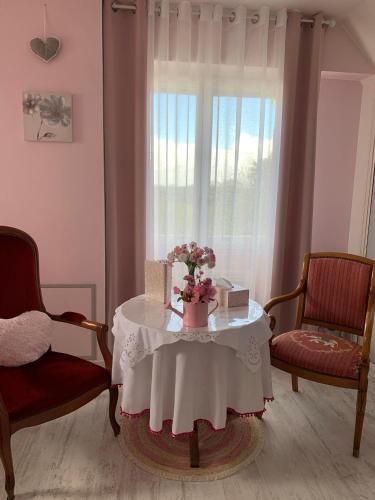 une table avec des fleurs devant une fenêtre dans l'établissement Les Grillettes, à Ploërmel